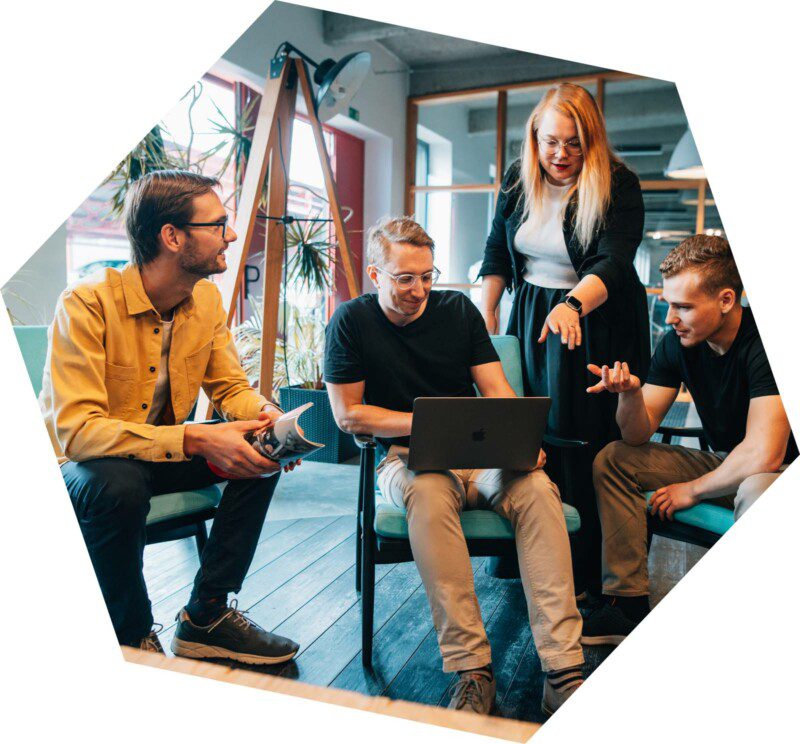 Čtyři členové agentury Včeliště u jednoho notebooku při plánování nebo řešení nějakého úkolu.