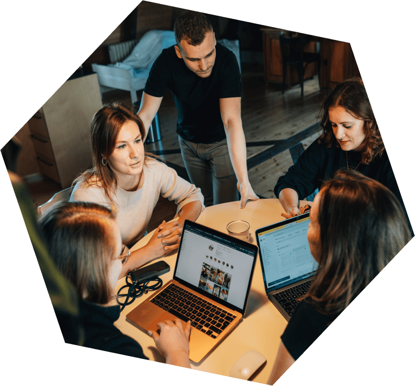 Skupina lidí diskutující u stolu s notebooky během online marketingového webináře.