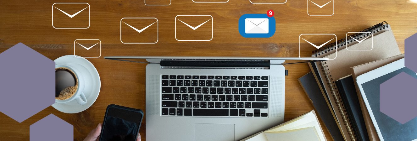 Notebook na stole s ikonami e-mailů, šálek kávy a smartphone, symbolizující e-mail marketing.