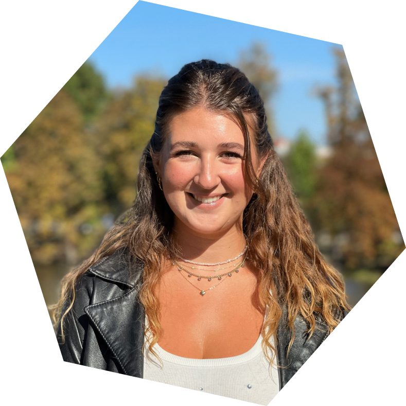 Usměvavá žena v kožené bundě na podzimním pozadí.