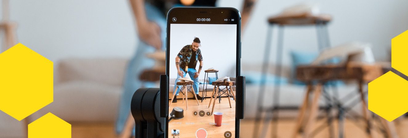 Muž s položen&yacute;m mobilem na stativu nat&aacute;č&iacute; video pro soci&aacute;ln&iacute; s&iacute;tě.