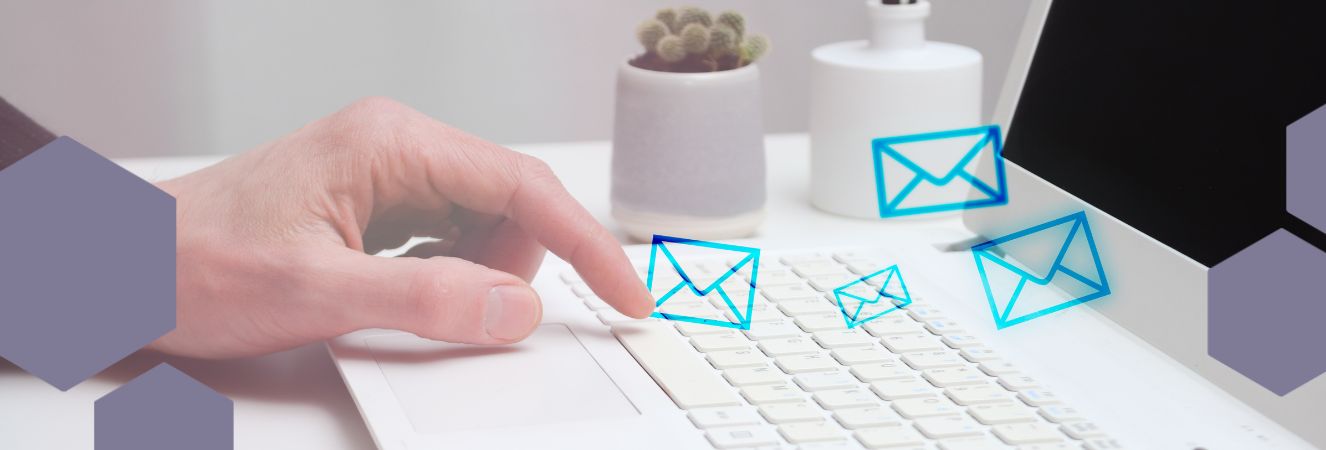 Ruka na kl&aacute;vesnici poč&iacute;tače, odes&iacute;laj&iacute;c&iacute; email, s n&aacute;znakem několika symbolů ob&aacute;lky, kter&eacute; let&iacute; z poč&iacute;tače.